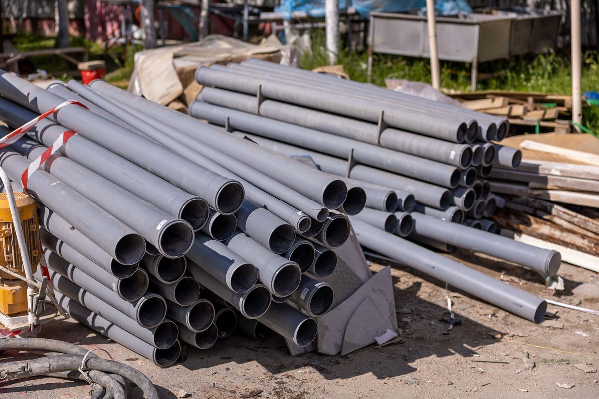Licensed stock photograph: stacked lengths of new drainage pipe on a construction site.